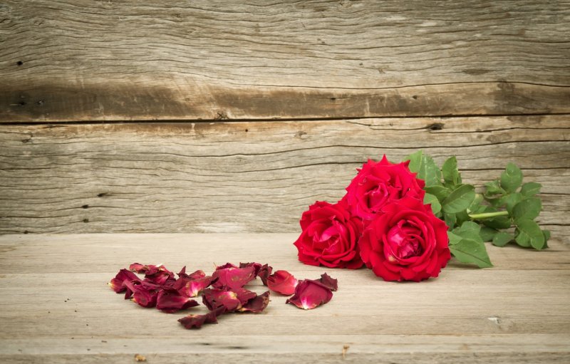 Лепестки роз на деревянном столе